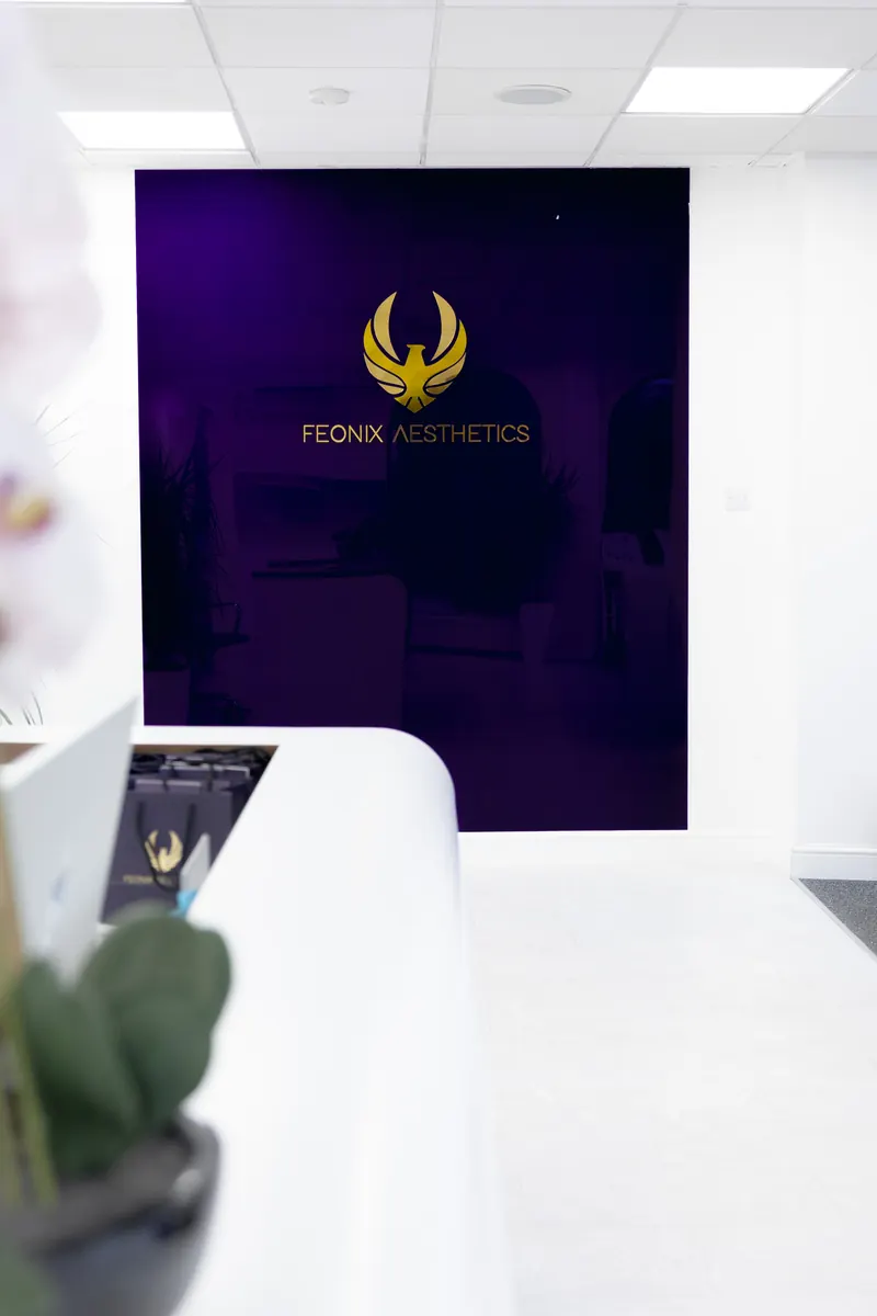 Reception at Feonix Aesthetics in Coventry, with the Feonix phoenix on a deep purple wall.